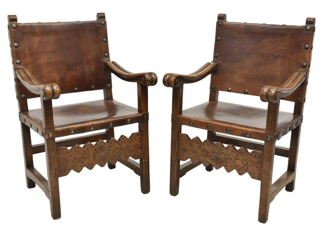 (2) SPANISH RENAISSANCE REVIVAL LEATHER ARMCHAIRS: (pair) Spanish Renaissance Revival armchairs, Posse Furniture, Los Angeles, late 20th c., frames in a walnut finish, with volute scrolled stiles, studded brown leather back and seat, rising on square 