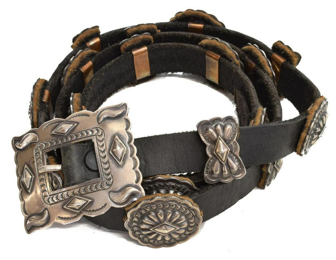 SOUTHWESTERN SILVER & LEATHER CONCHO BELT: Southwest Native American sterling silver and leather belt, marked MR (Michael R. Rogers, Native American), the leather strap fitted with (1) buckle and (18) conchos, each with applied copper loop ver
