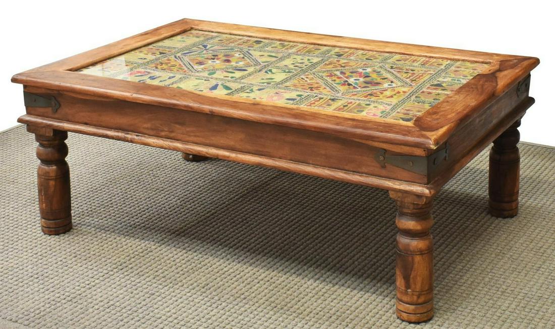 INDIA WOOD FRAME GLASS TOP TAPESTRY COFFEE TABLE: India wood coffee table, 20th c., having glass insert to tabletop, above embroidered tapestry, rising on turned legs, approx 18"h, 46.75"w, 30.75"d Start Price: $100.00