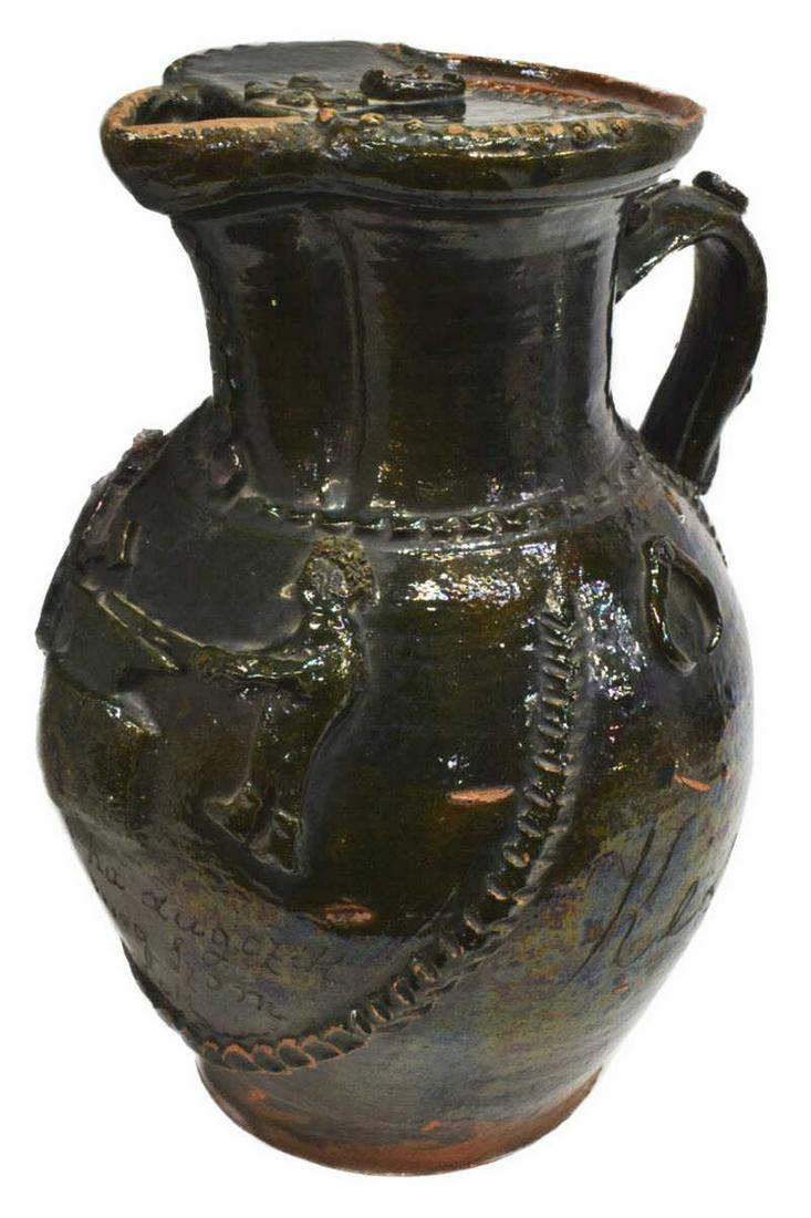 LARGE BLACKSMITH MOTIF GLAZED EARTHENWARE PITCHER: Large glazed earthenware pitcher, 19th c., possibly Hungarian, applied blacksmith figures working at the anvil, symbols including compasses, tongs, and horseshoes, incised text as pictured, retaining 
