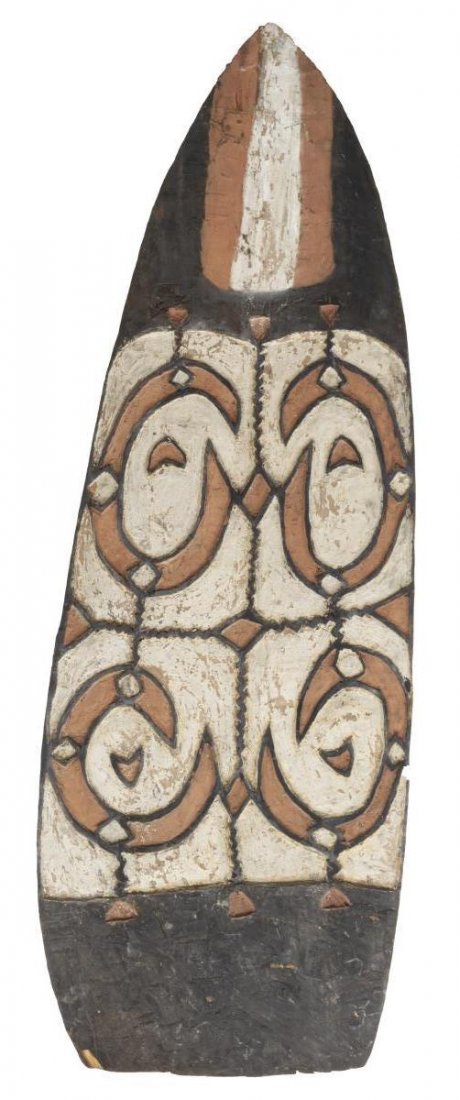 WARRIOR SHIELD, ASMAT PEOPLE, NEW GUINEA: Large carved wood war shield, Asmat People, New Guinea, 20th c., carved geometric designs with faded peeling polychrome paint, a wood handle at back side, 68.25"h, 23.75"w Start Price: $150.00