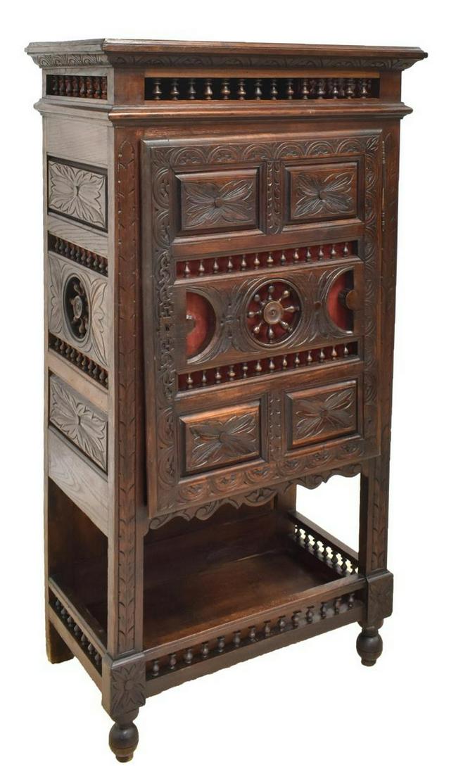 FRENCH BRETON CARVED OAK CABINET: French Breton carved oak cabinet, 19th c., having open spindle ornamentation throughout, heavily carved with floral motifs, single-door cabinet accented by large scrolled iron escutcheon opening to si