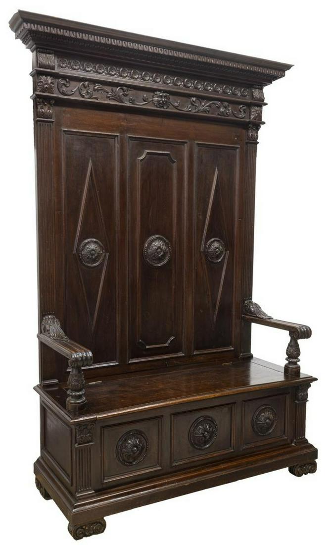 ITALIAN RENAISSANCE REVIVAL WALNUT HALL BENCH: Italian Renaissance Revival carved walnut hall bench, 19th c., accented by rosette, floral and grotesque carving, having molded cornice atop paneled backboard, lift-top seat enclosing open interior, a
