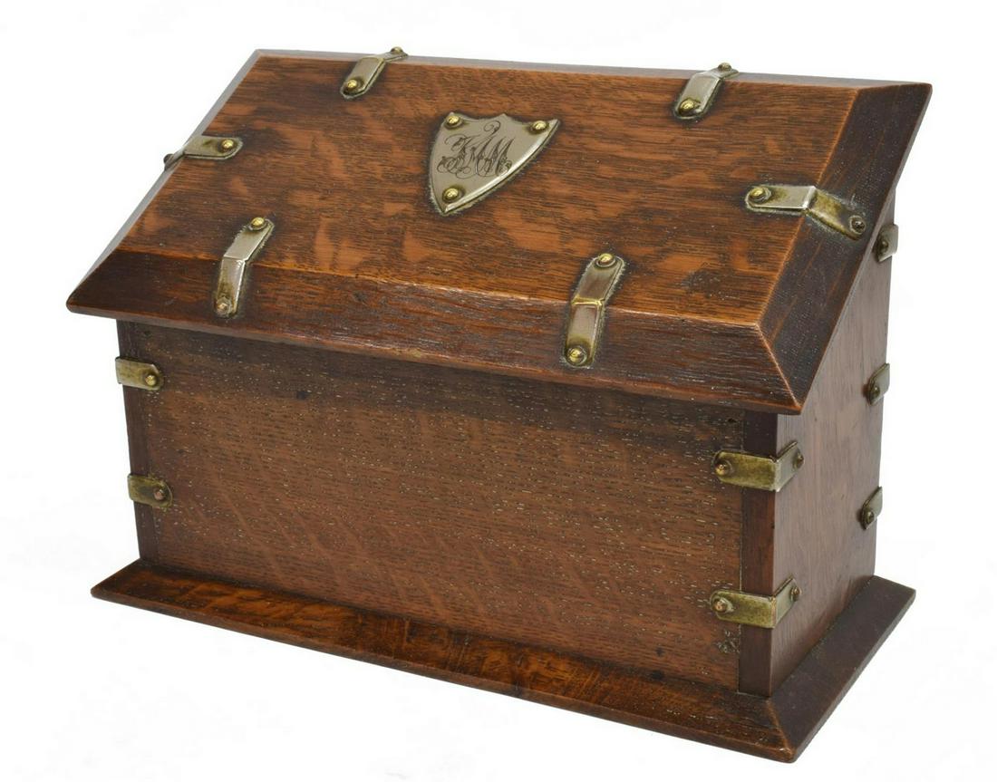 ENGLISH EDWARDIAN OAK SLANT LID STATIONARY BOX: English Edwardian oak stationary desk box, early 20th c., a slant lid with monogrammed shield-form plaque, over the rectangular case with brass and silver tone metal bindings, slotted interior, on a s