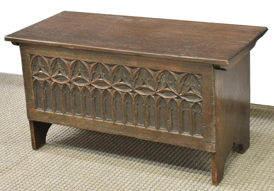 DIMINUTIVE ENGLISH GOTHIC STYLE OAK TRUNK: English Gothic style oak trunk, 20th c., rectangular case, top on iron strap hinges, open interior, front panel carved with Gothic-inspired tracery, rising on bracket feet, approx 19"h, 36"w, 16"d Sta