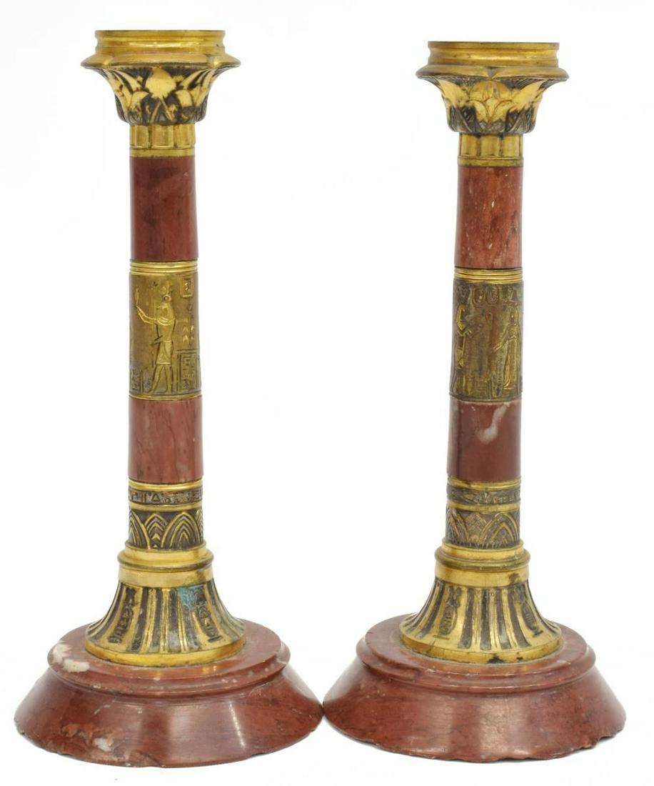 (2) EGYPTIAN REVIVAL MARBLE CANDLESTICKS: (lot of 2) Egyptian Revival marble candlesticks, late 19th c., having one candle cup above marble standard, featuring central gilt metal image depicting Egyptian immortals, Osiris, Ra and Anubis, on c