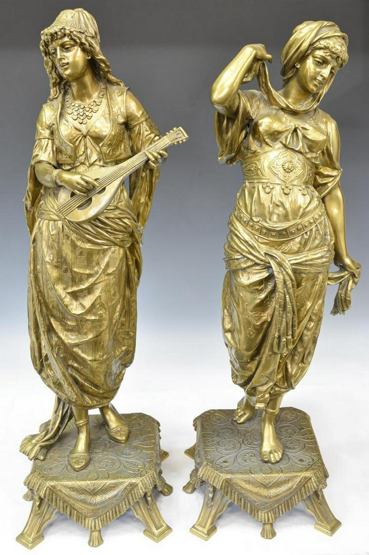 (2) LARGE ORIENTALIST GILT METAL HAREM FIGURES: (lot of 2) Large Orientalist gilt metal figures, one playing a stringed instrument while the other dances, standing on a platform base modeled as a draped rug with tassel trim, approx 33.75"h, base: a