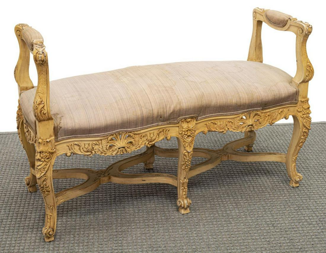 LOUIS XV STYLE CARVED BANCH: Louis XV style bench, 20th c., accented with foliate, mask and pierced carving, raised padded arms framing stained upholstery, rising on stretcher joined scroll foot cabriole legs, 28.5"h, 43.5"w, 17"