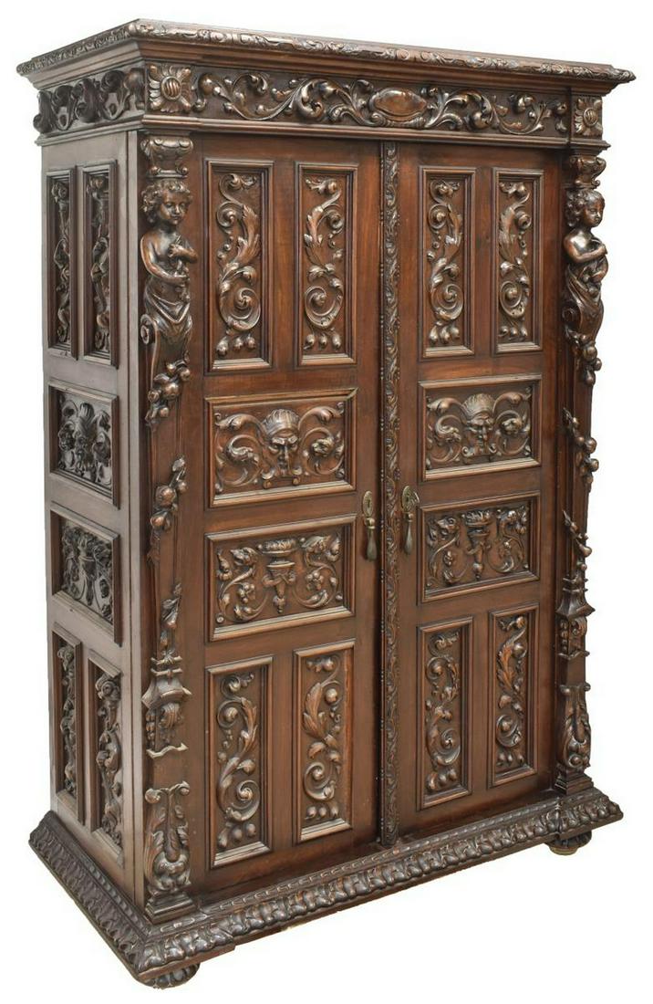 SPANISH RENAISSANCE REVIVAL CARVED OFFICE CABINET: Spanish Renaissance Revival walnut office cabinet, early 20th c., frieze with scrolling foliates in relief, double doors flanked by carved figural pilasters and trailing fruit, paneled door fronts wit