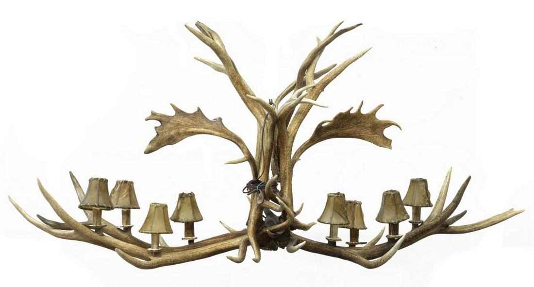 LARGE RUSTIC EIGHT-LIGHT ANTLER CHANDELIER: Rustic antler chandelier, fashioned with various antlers, and fitted with eight lights, each with hide shades, some splits to hide, approx 31"h, 69"w, 27"d Start Price: $200.00