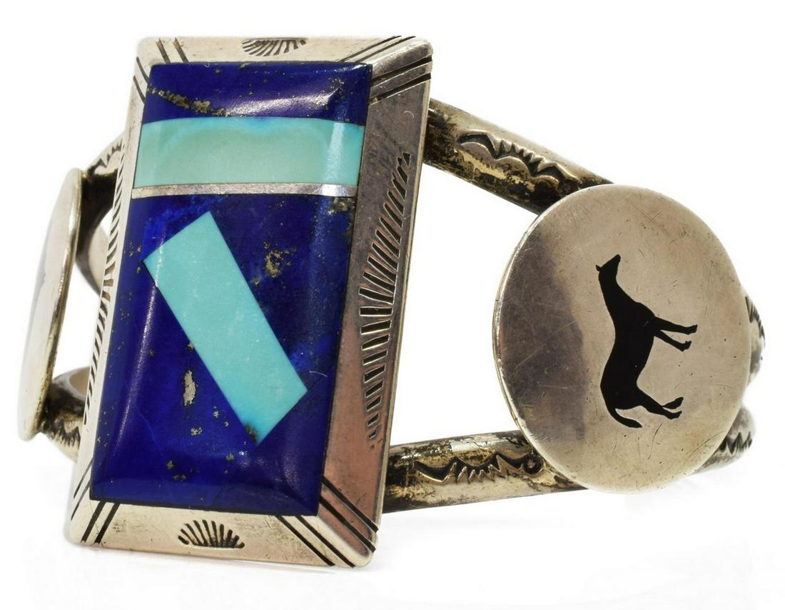 D. BITSUIE NAVAJO LAPIS & TURQUOISE SILVER CUFF: Native American silver (content unknown) cuff bracelet, D. Bitsuie (Navajo, 20th/ 21st c.), central lapis lazuli plaque inlaid with turquoise, framed by circular elements with black enamel horses, sta