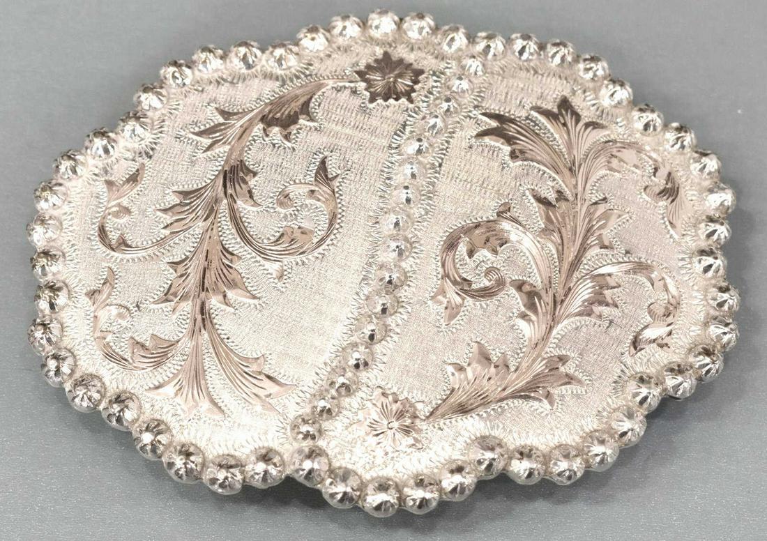 VOGT SILVERSMITHS WESTERN GOLD& SILVER BELT BUCKLE: Vogt Silversmiths hand engraved sterling silver and 10kt gold overlay belt buckle, undulating beaded trim, gold accented foliates on a textured ground, presented in the original branded box, hallmarke