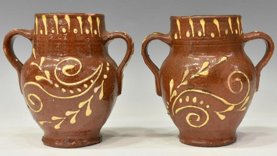 (2) AMERICAN SLIP-DECORATED REDWARE POTTERY VASES: (pair) American redware pottery vessels/ vases, with applied double strap handles, scrolled yellow slip decoration, small chips and glaze losses, approx 6"h; 1.75lbs total Start Price: $80.00