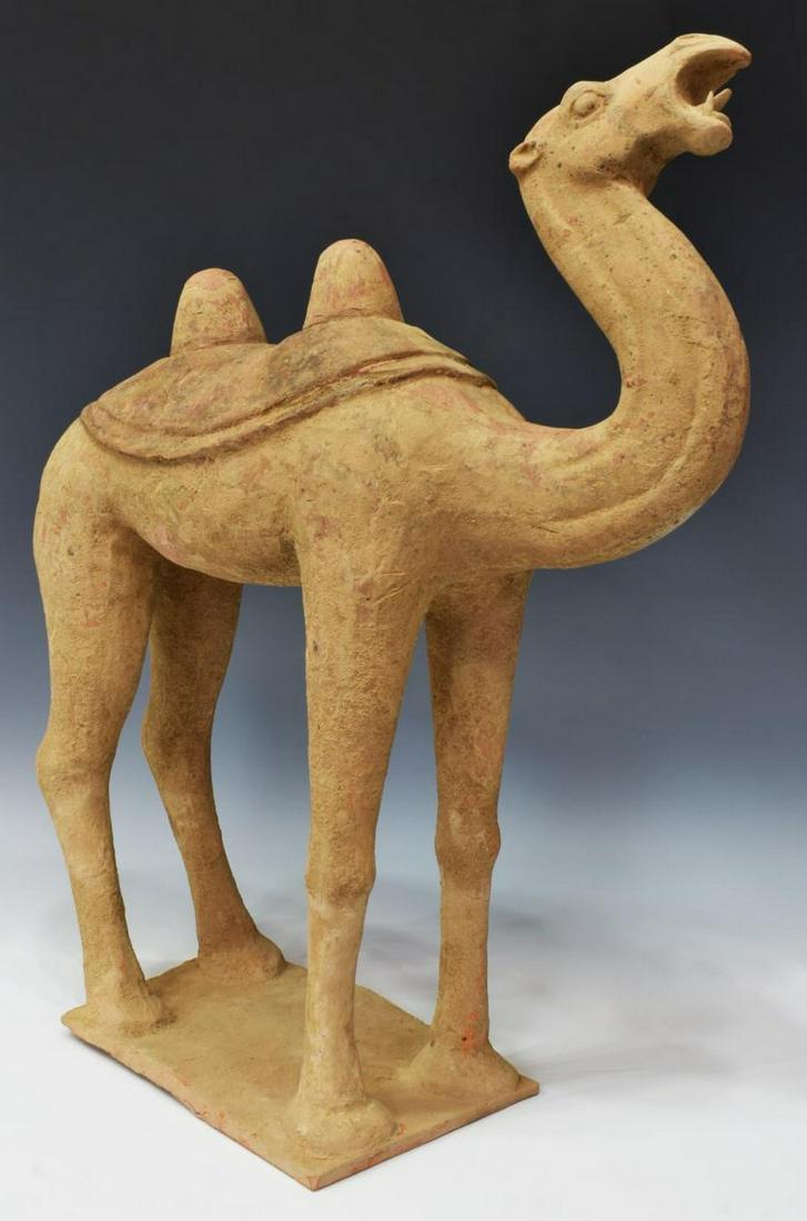 CHINESE TANG DYNASTY POTTERY BACTRIAN CAMEL: Chinese pottery Bactrian camel, Tang Dynasty, c. 618-907 CE, modeled with mouth open, well-detailed features, long s-curve neck, two humps covered with saddle blanket, on an integral plinth base, lack
