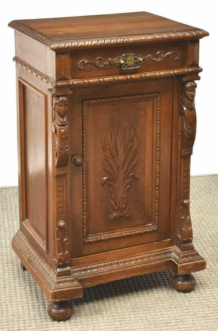 ITALIAN RENAISSANCE REVIVAL WALNUT BEDSIDE CABINET: Italian Renaissance Revival walnut bedside cabinet, late 19th c., fitted with a single drawer over cabinet door with foliate carving, flanked by figural pilasters, rising on bun feet, wood splits to t