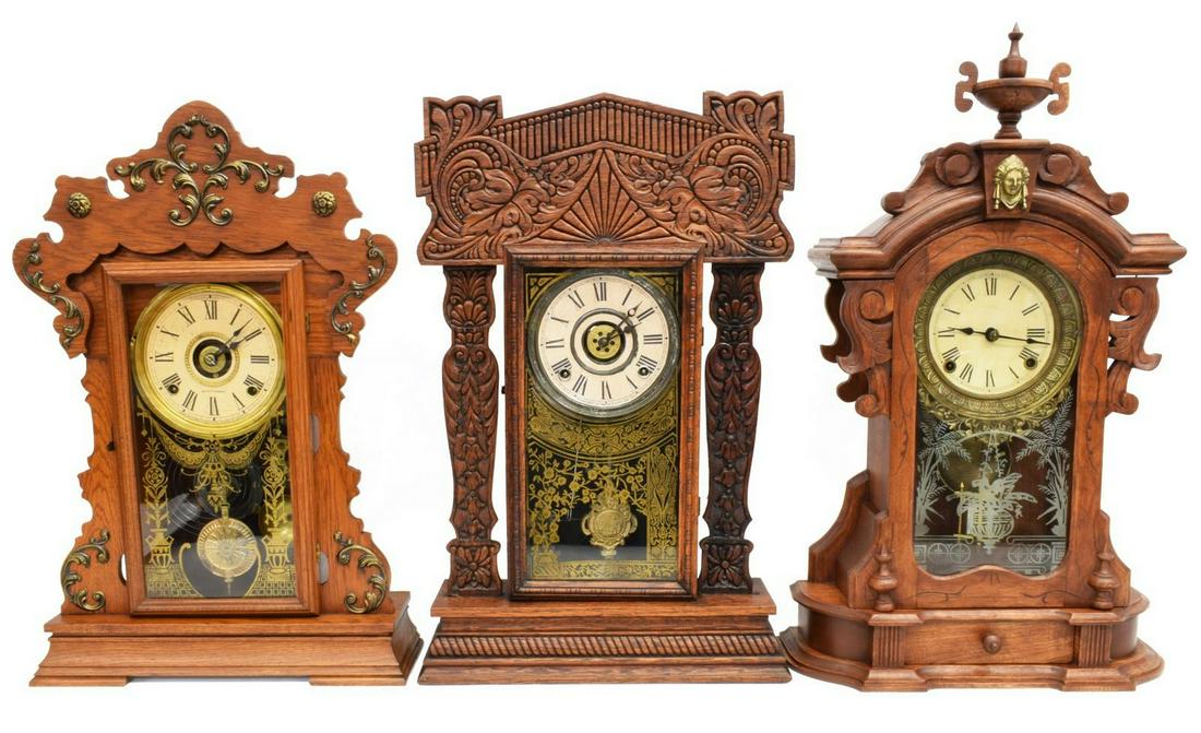 (3) AMERICAN GINGERBREAD KITCHEN SHELF CLOCKS: (lot of 3) American kitchen clocks, late 19th/ early 20th c., each in a "gingerbread" case, with time and strike movement, Roman numerals, comprising: (1) Ansonia "Monarch" model, in a walnut case, gl