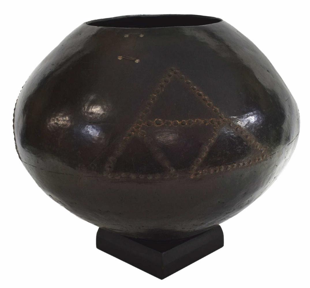 LARGE AFRICAN TRIBAL ZULU GEOMETRIC CLAY BEER POT: Large Zulu clay beer pot, South Africa, the vessel having raised geometric pattern, old wire stabilization to hairline at one side, resting on a wood base, pot only: approx 12"h, 16"w, approx 13.25lbs