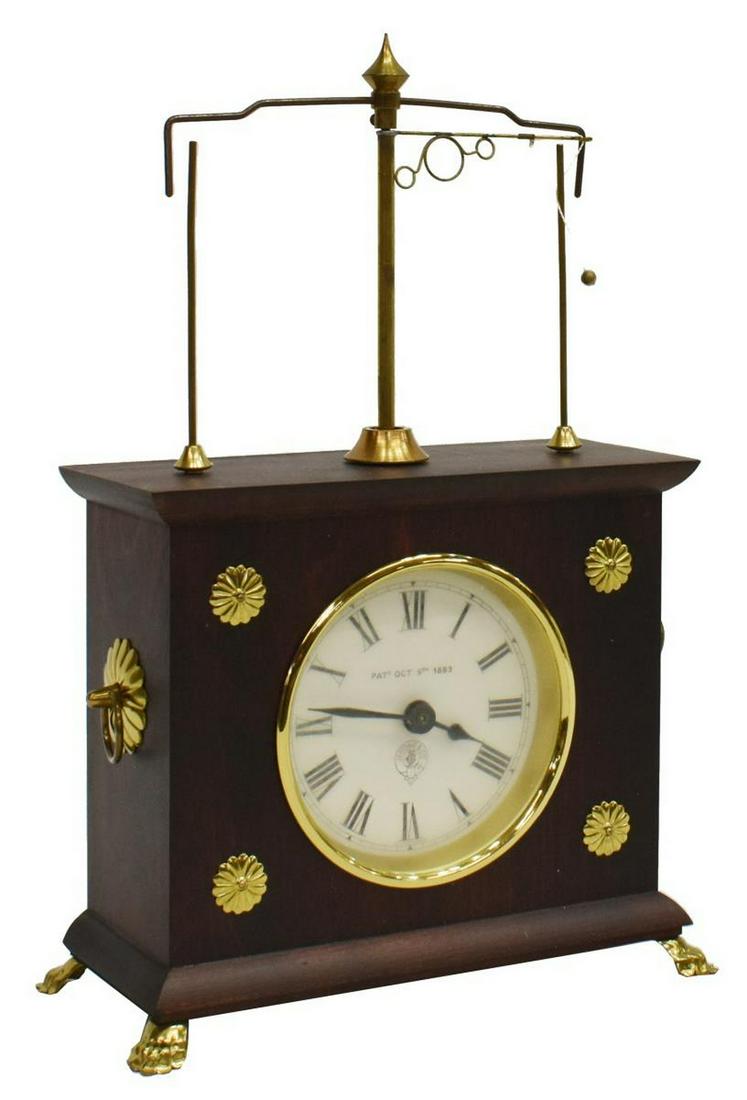 JEROME & CO HOROLOVAR FLYING PENDULUM CLOCK IN BOX: Jerome & Co. Horolovar flying pendulum novelty clock, in original box, flying pendulum over case in a mahogany finish, white dial with roman numerals, rising on gilt metal paw feet, observed operating