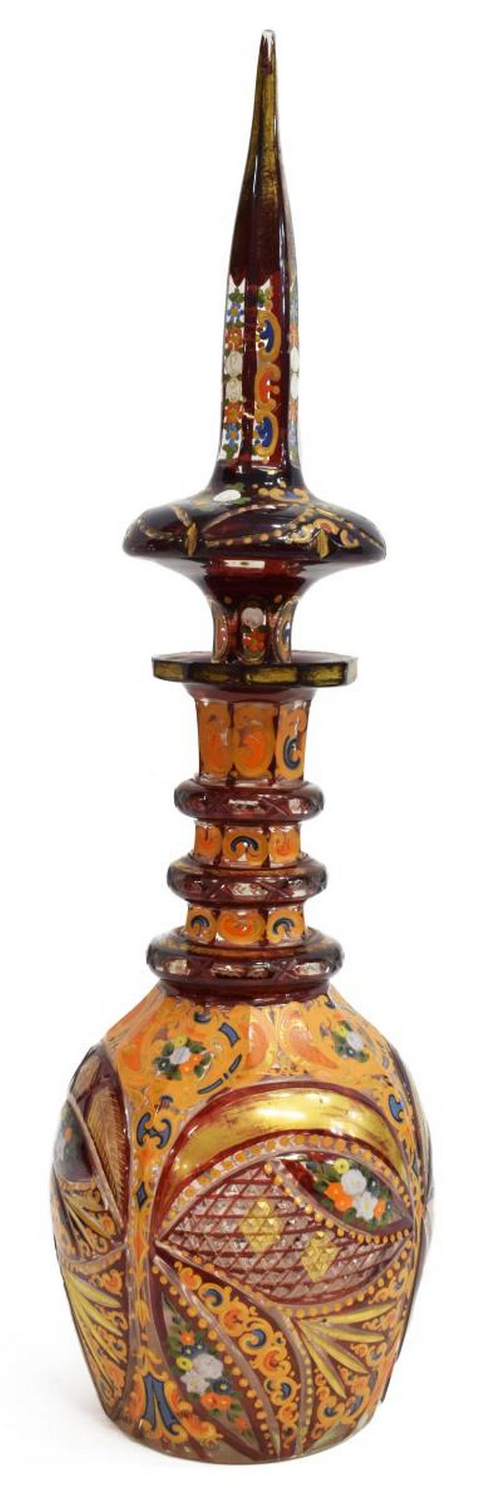 BOHEMIAN CASED PARCEL GILT PERSIAN DECANTER: Bohemian ruby cased and enameled art glass decanter, made for the Islamic market, 19th c., having an elongated steeple-form stopper resting in a ring neck, the cut and shaped body with parcel gilt and