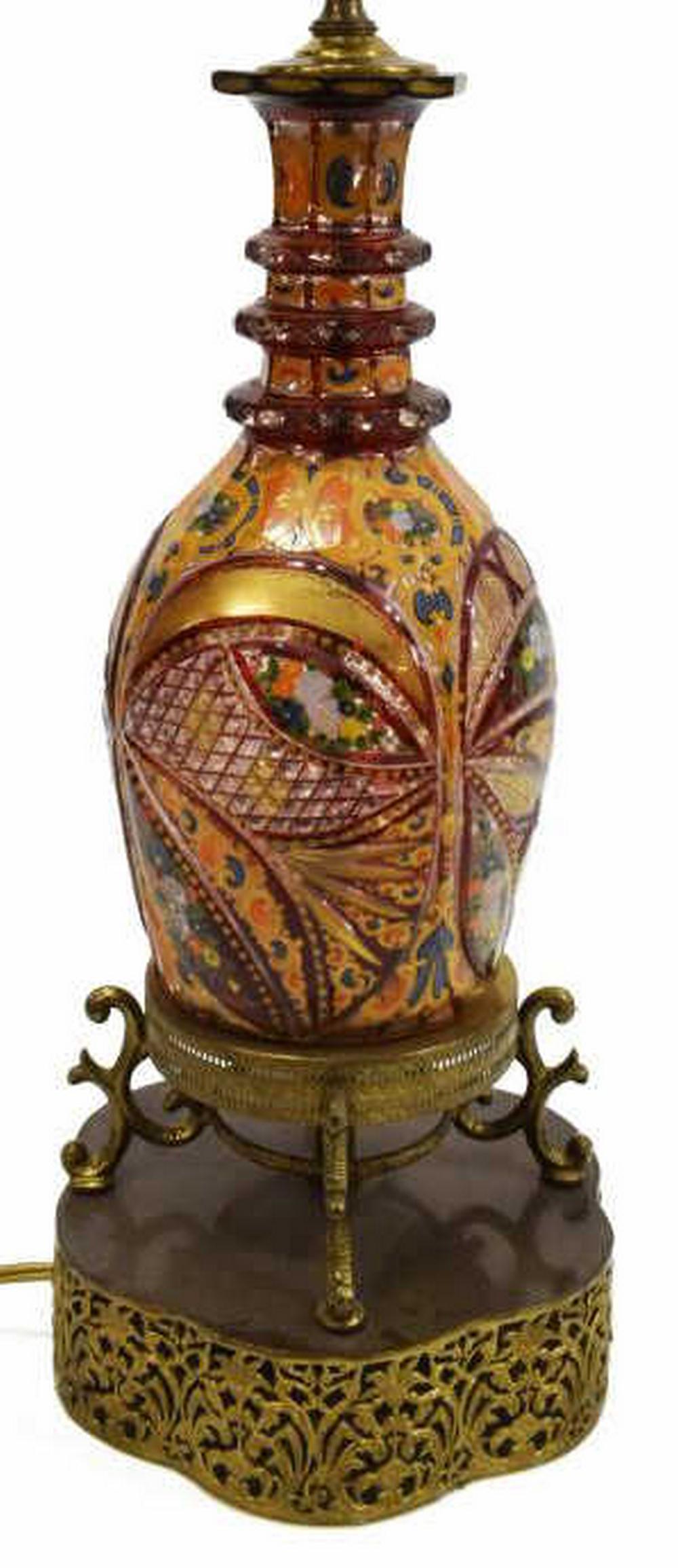 BOHEMIAN CASED PARCEL GILT PERSIAN DECANTER LAMP: Bohemian ruby cased and enameled art glass decanter, made for the Islamic market, 19th c., now fashioned as a table lamp, the cut and shaped body with parcel gilt and polychrome painted enamel flowers