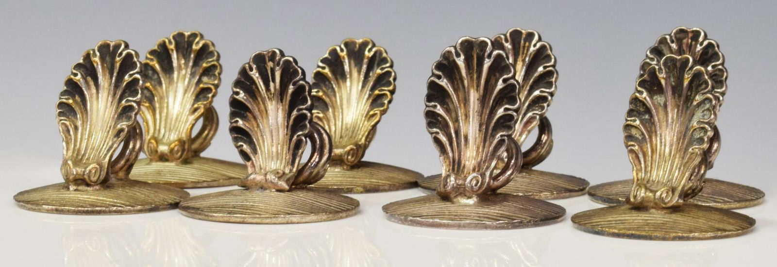 8) CHRISTOFLE SILVERPLATE SHELL PLACE CARD HOLDERS: (lot of 8) French Christofle silver plate place card holders, shell form on a textured circular base, approx 0.75"h, 7/8"diam; 0.25lbs total Start Price: $80.00
