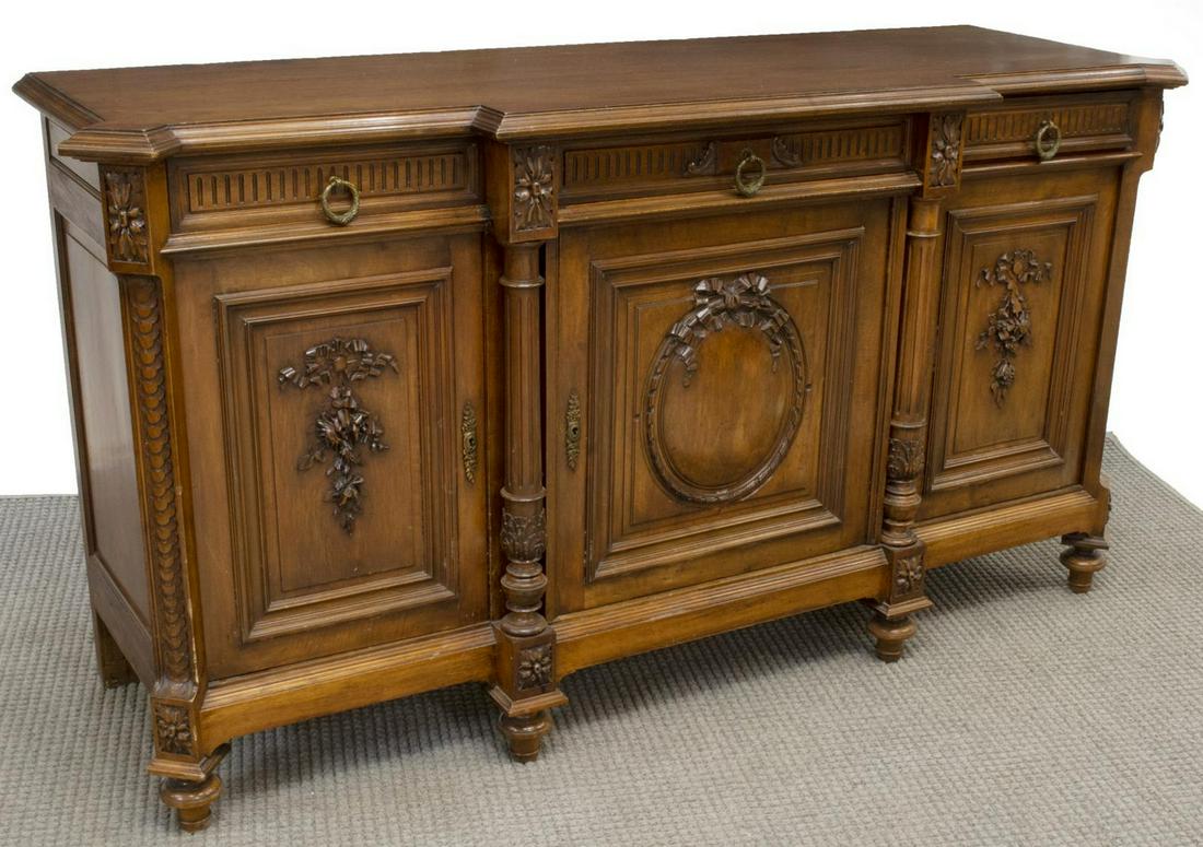 FRENCH LOUIS XVI STYLE BREAKFRONT SIDEBOARD: French Louis XVI style walnut breakfront sideboard, 19thc., three drawers over three doors, the center drawer flanked by ribbed columns, the whole with ribbon and floral decoration, rising on tapered 