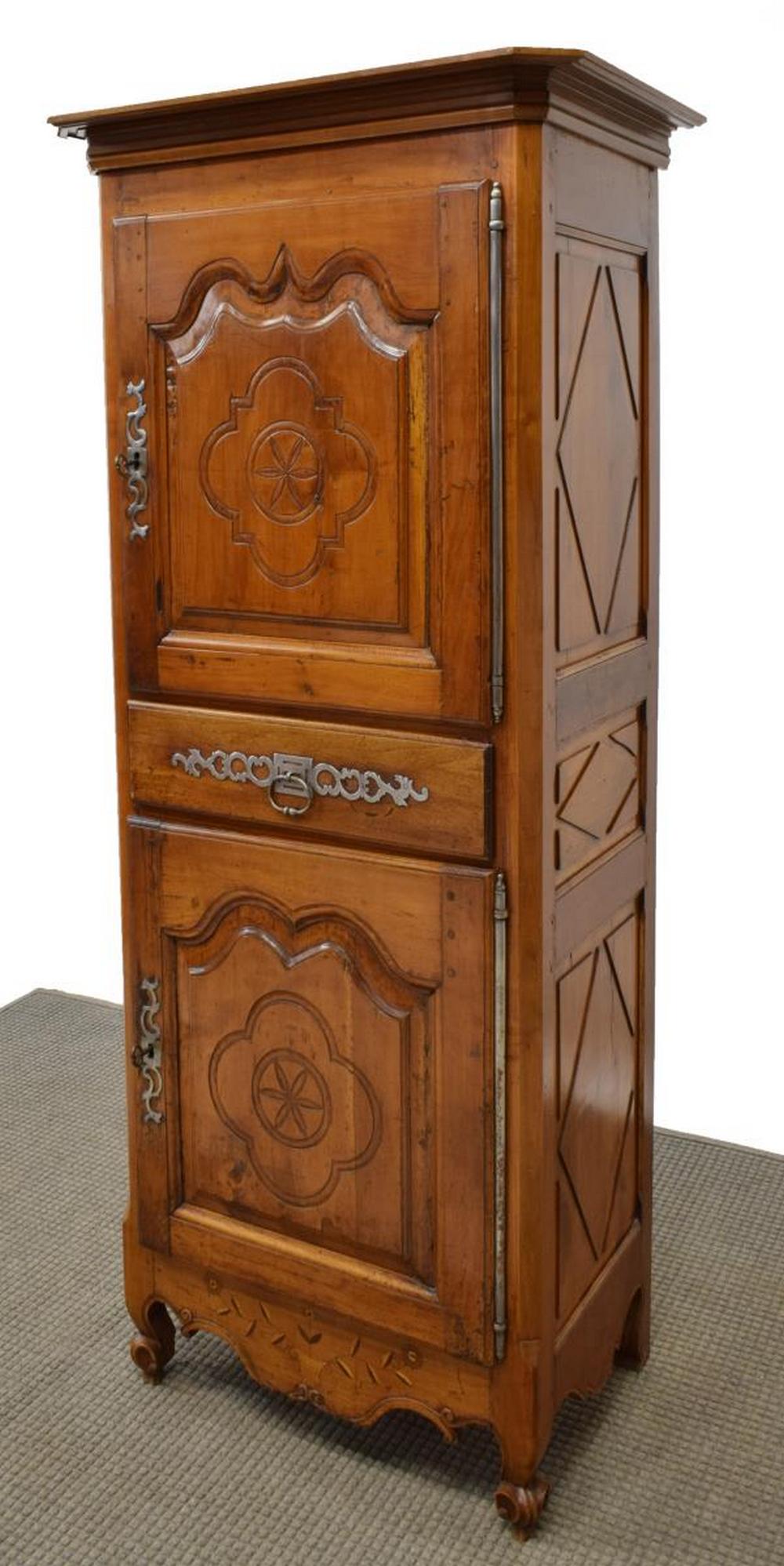LOUIS XV STYLE FRUITWOOD BONNETIERE, 19TH C.: French Louis XV style fruitwood bonnetiere, 19th c., having cornice top, atop rectangular case fitted with center drawer flanked by upper and lower cabinet doors on exterior hinges, carved foliate and