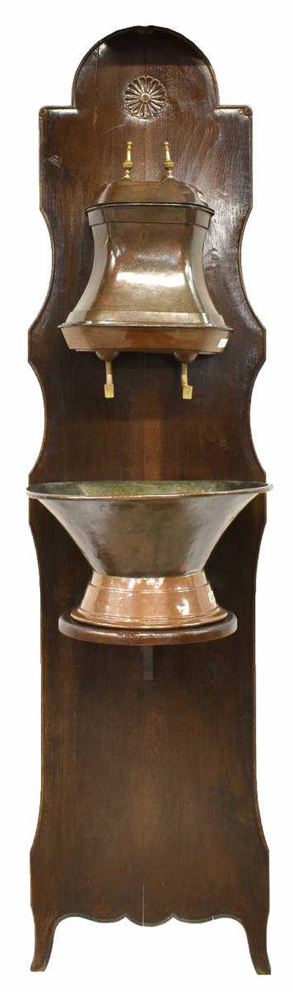 FRENCH PROVINCIAL COPPER LAVABO ON WALNUT STAND: French Provincial copper lavabo, mounted on walnut backing, late 19th c., brass finials on the lidded copper vessel with etched flower issuing two brass spigots, over copper basin, all mounted on back