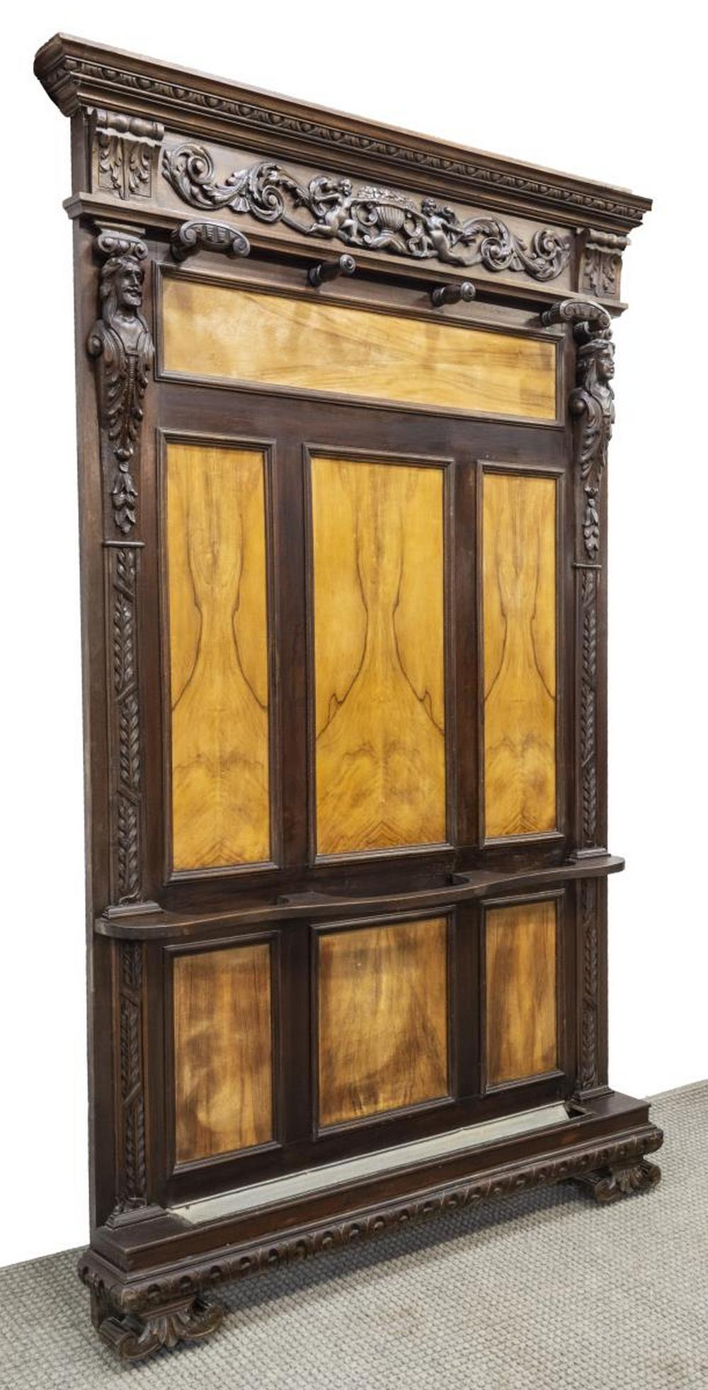 RENAISSANCE REVIVAL FIGURAL CARVED HALL TREE: Italian Renaissance Revival figural carved hall tree, 19th c., with crown molding, extensive carving of figural heads, cherubs, garden-urns, and scrolling foliates, fitted with four coat hooks, umbrel