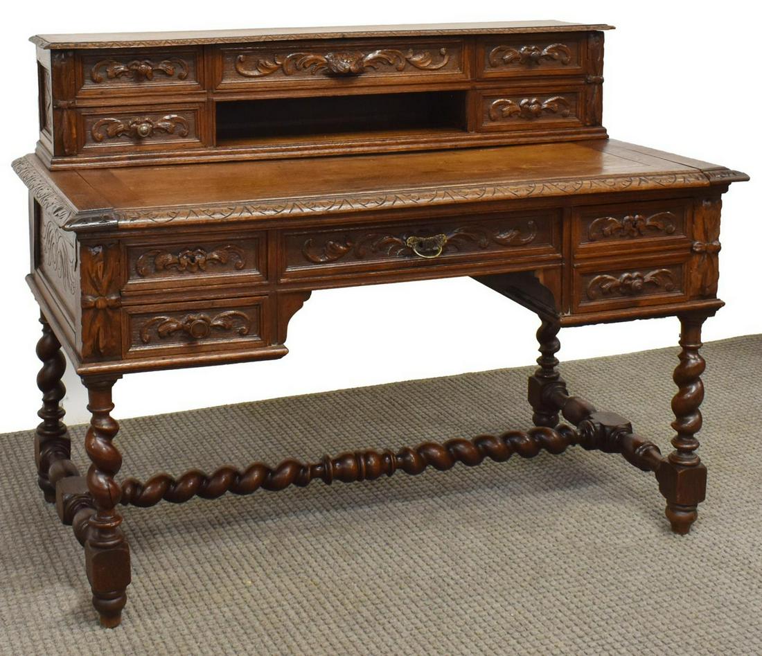 FRENCH HENRI II STYLE CARVED OAK WRITING DESK: French Henri II style oak writing desk, 19th c., having extensive carved foliates throughout, with a stepback five-drawer gallery, over rectangular writing surface, fitted with five additional drawers