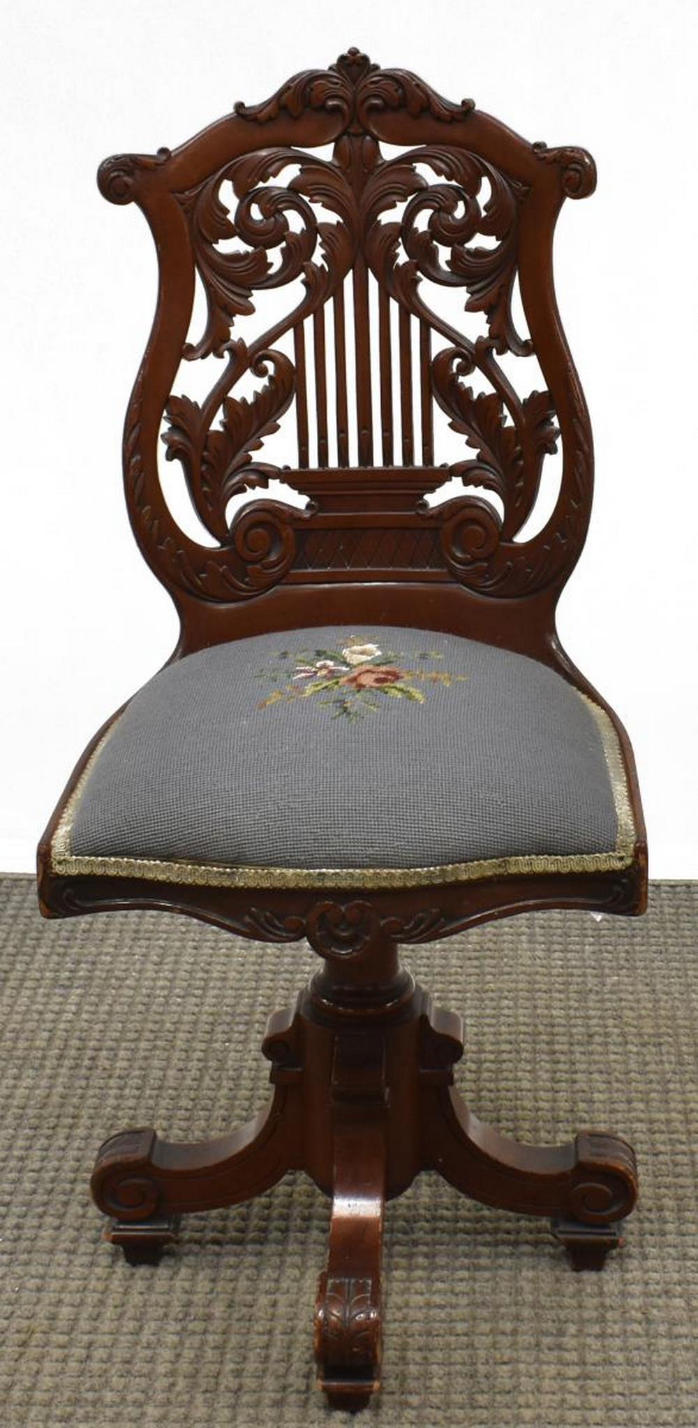AMERICAN CLASSICAL MAHOGANY SWIVEL PIANO CHAIR: American Classical mahogany piano chair, 19th c., harp-shaped back with scrolling foliate carving, needlepoint upholstered seat, swivels on center pedestal, ending in scrolled legs, approx 37"h, 16.75