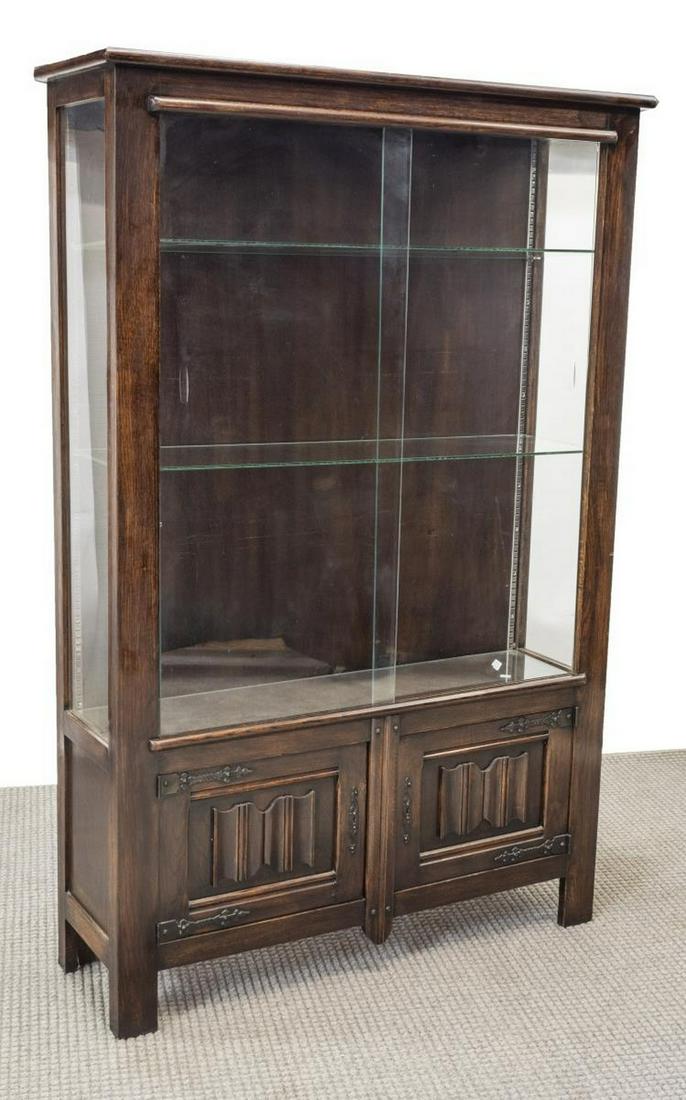 FRENCH GLAZED VITRINE DISPLAY CABINET: French vitrine/ display cabinet, 20th c., glazed side panels, sliding glass door to front, over double-door cabinet with linenfold carving, elaborate strap hinges and scrolled escutcheon, rising on bl