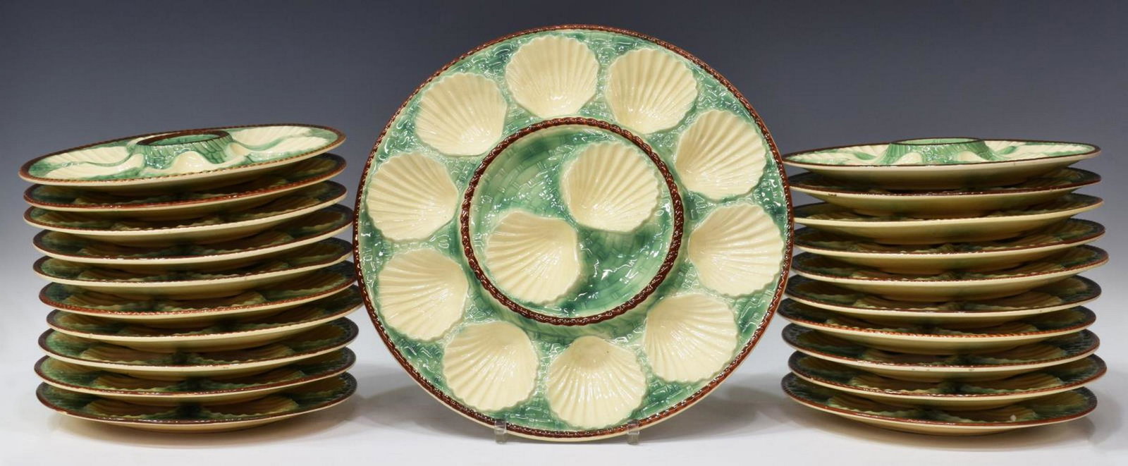 (21) FRENCH MAJOLICA OYSTER SERVICE SET: (lot of 21) French majolica oyster service, early 20th c., with scalloped shell shaped wells, green against white ground with embossed basket weave pattern, including: (20) plates, one with small chip