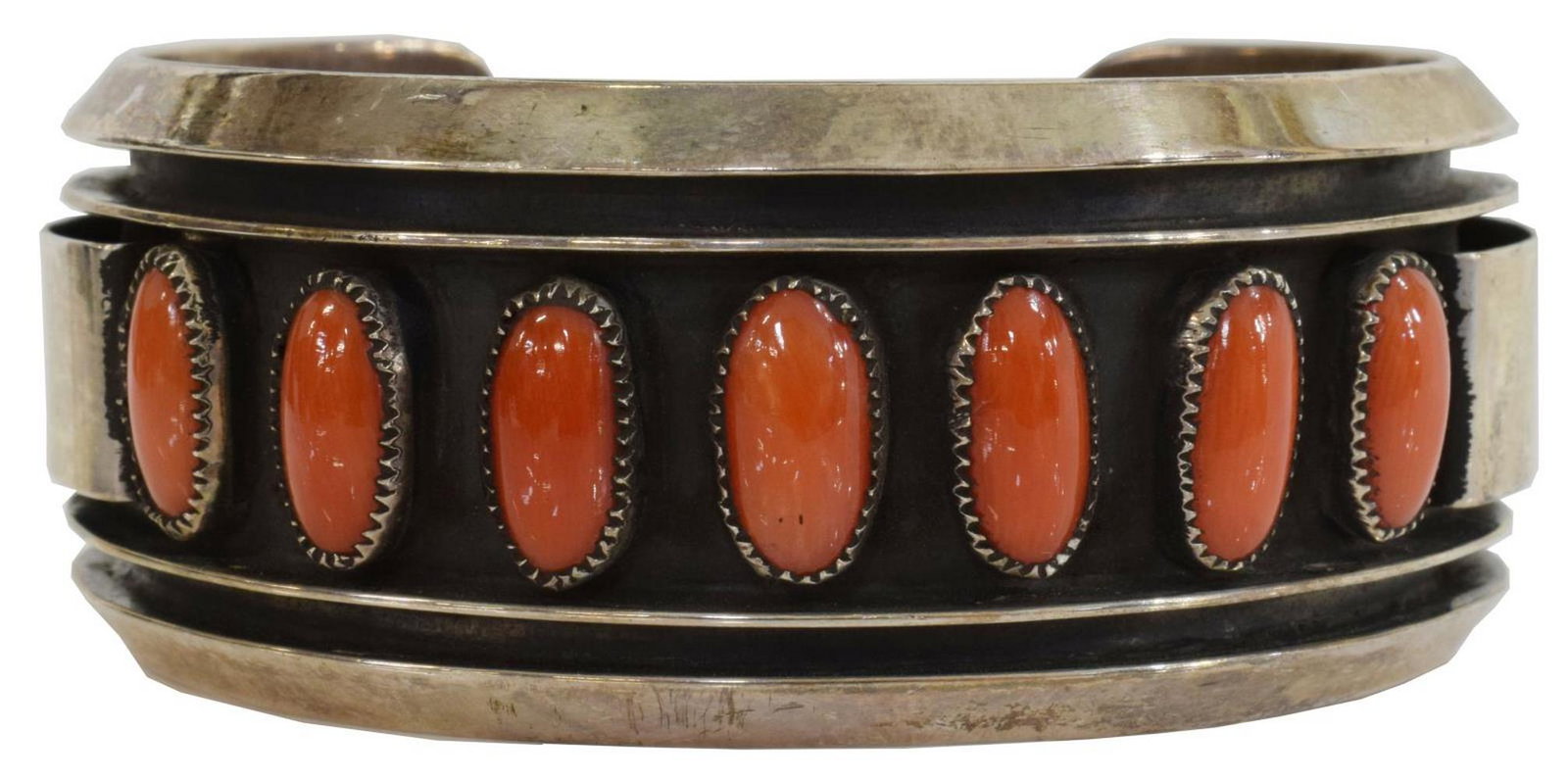 JACKIE SINGER NAVAJO SHADOWBOX RED CORAL CUFF: Native American silver (content unknown) cuff bracelet, Jackie Singer (Navajo, 20th c.), with seven recessed bezel-set red coral cabochons, approx 1"w, interior: (end to end) approx 5 7/8"l, gap: appr