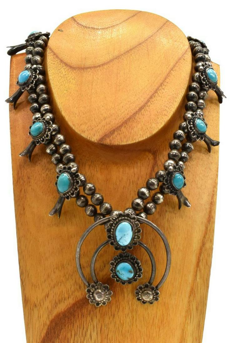NATIVE AMERICAN TURQUOISE SQUASH BLOSSOM NECKLACE: Native American silver (content unknown) squash blossom necklace, signed LOS (?), bench bead strand, eight blossoms, central naja with flower terminals, all set with turquoise cabochons, approx 24.5"l