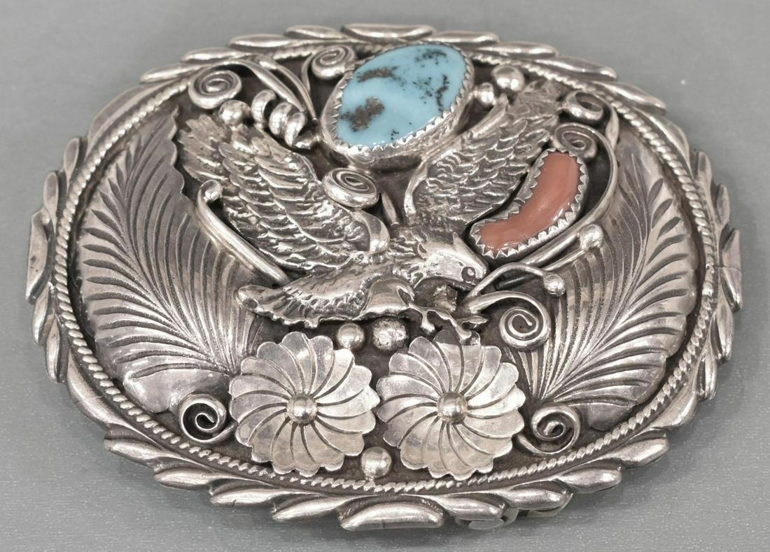 ROBERT BECENTI NAVAJO STERLING EAGLE BELT BUCKLE: Native American sterling silver belt buckle, signed RB (Robert Becenti, Navajo, 1949-2001), finely worked oval form with spread wing eagle, feathers and flowers, fitted with a turquoise and red coral,