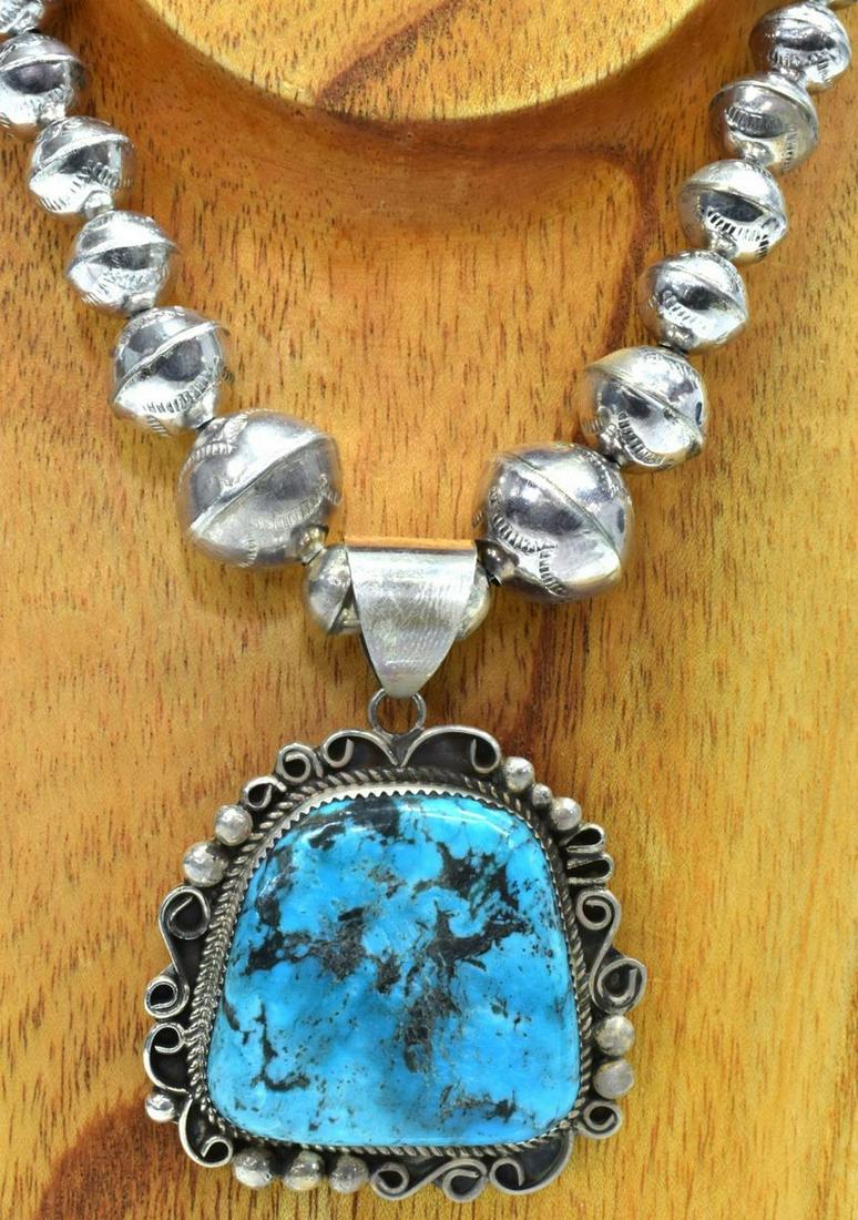 LESLIE NEZ NAVAJO STERLING & TURQUOISE NECKLACE: Native American sterling silver necklace, Leslie Nez (Navajo, b.1978), central pendant fitted with large polished bezel-set turquoise plaque, in beaded and twisted wire frame, on graduated bench bead