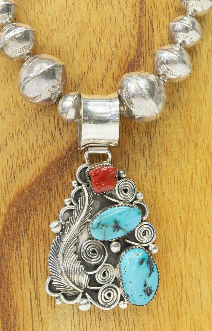 NATIVE AMERICAN STERLING TURQUOISE CORAL NECKLACE: Native American sterling silver necklace, hallmarked K, central pendant with polished bezel-set turquoise and red coral, feather, silver beads, and scrolled accents, on graduated bench bead strand, ap