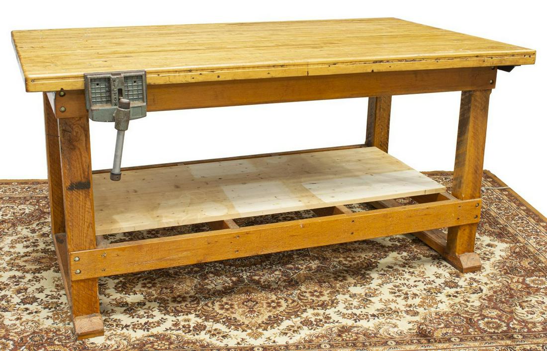 RUSTIC CRAFTSMAN'S WOOD WORKBENCH TABLE: Rustic craftsman's workbench, having rectangular top, with dog holes, iron crank vise, raised on trestle base joined by medial shelf, approx 35.75"h, 71"w, 46"d **Provenance: From the estate of Dr. Ja