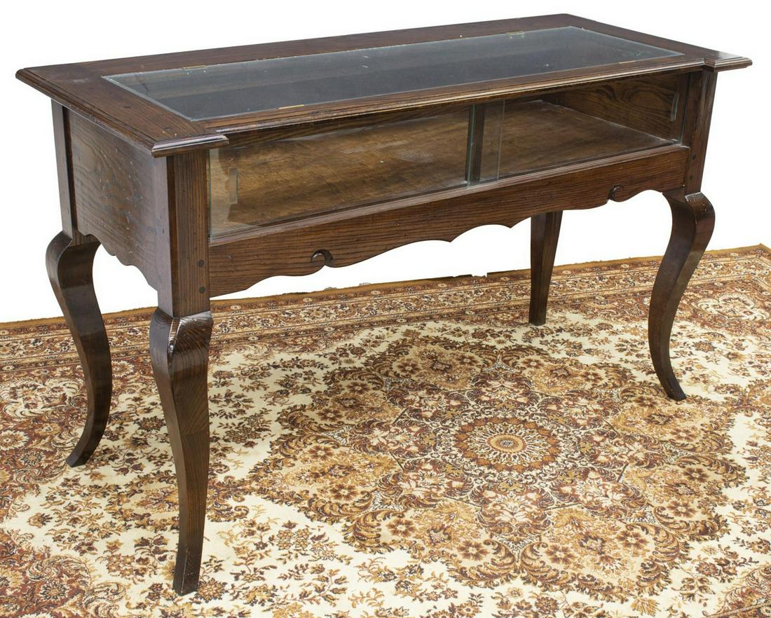 OAK FRAMED RETAIL STORE DISPLAY CASE TABLE: Retail display case, late 20th c., oak frame with glazed top, front with two sliding glass doors, interior lighting, scrolled apron, rising on cabriole legs, approx 36.5"h, 60"w, 24.5"d Start Price: $