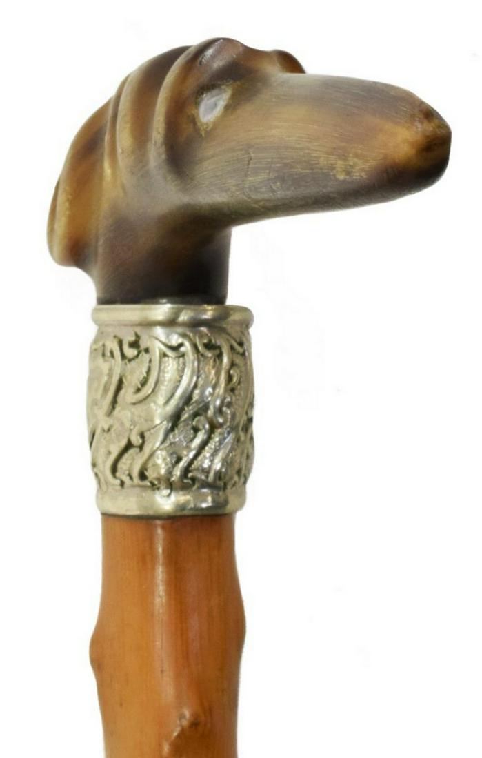 ANTIQUE FIGURAL CARVED HORN DOG HEAD WALKING CANE: Gent's figural carved horn and wood walking cane, likely early 20thc., the handle in the form of a dog head with inset eyes, silver tone metal color with open cartouche (dent), approx 33"l, 0.50lbs **