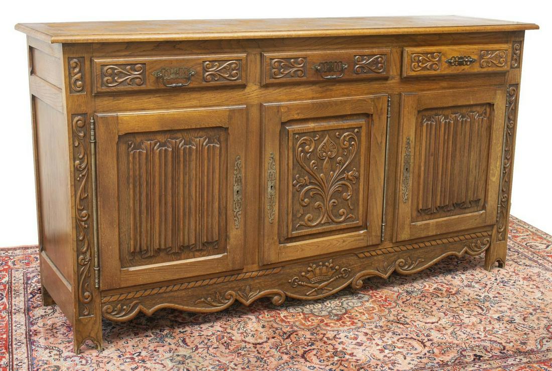 FRENCH MEDIEVAL STYLE CARVED OAK SIDEBOARD: French Medieval style carved oak sideboard, 20th c., having rectangular parquetry top, over case fitted with three frieze drawers, three lower cabinet doors with linenfold and foliate carving, opening
