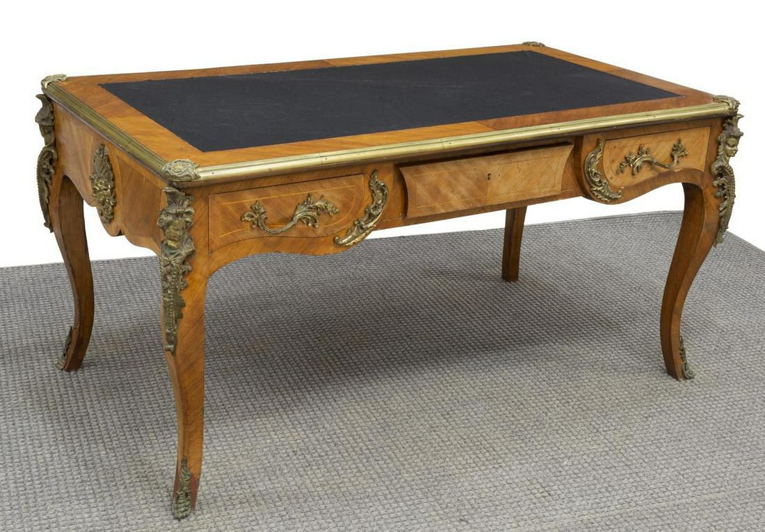 FRENCH LOUIS XV STYLE ORMOLU-MOUNTED BUREAU PLAT: French Louis XV style writing desk, early 20th c., a partners desk, decorated with figural and mask ormolu, the top with brass capped edges over three frieze drawers, rising on cabriole legs, lacking 