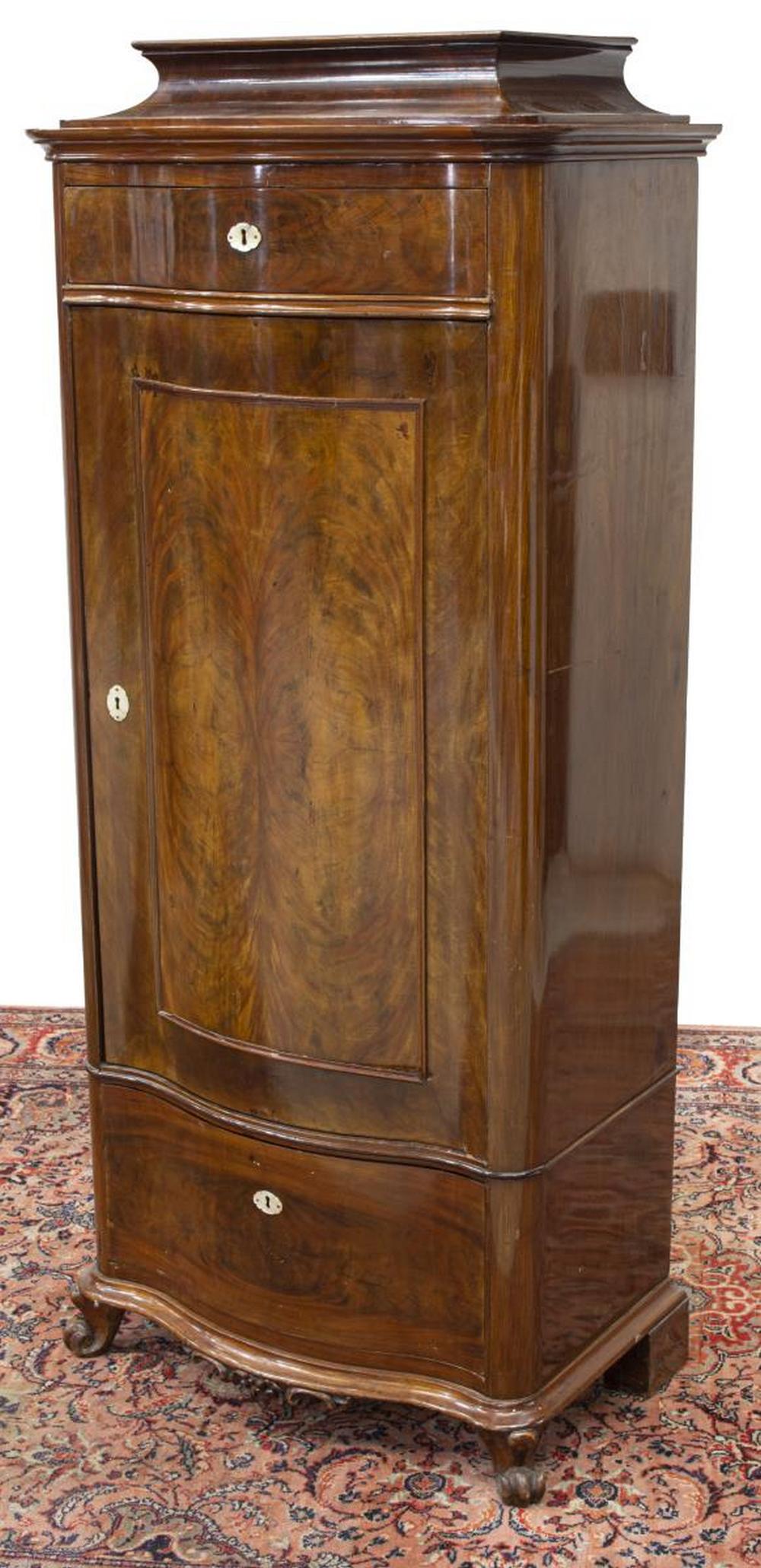 BIEDERMEIER SERPENTINE FRONT MAHOGANY CABINET: Biedermeier figured mahogany cabinet, 19th c., having raised top, serpentine-front case, fitted with upper frieze drawer, single cabinet door opening to four interior shelves, over lower drawer, all w