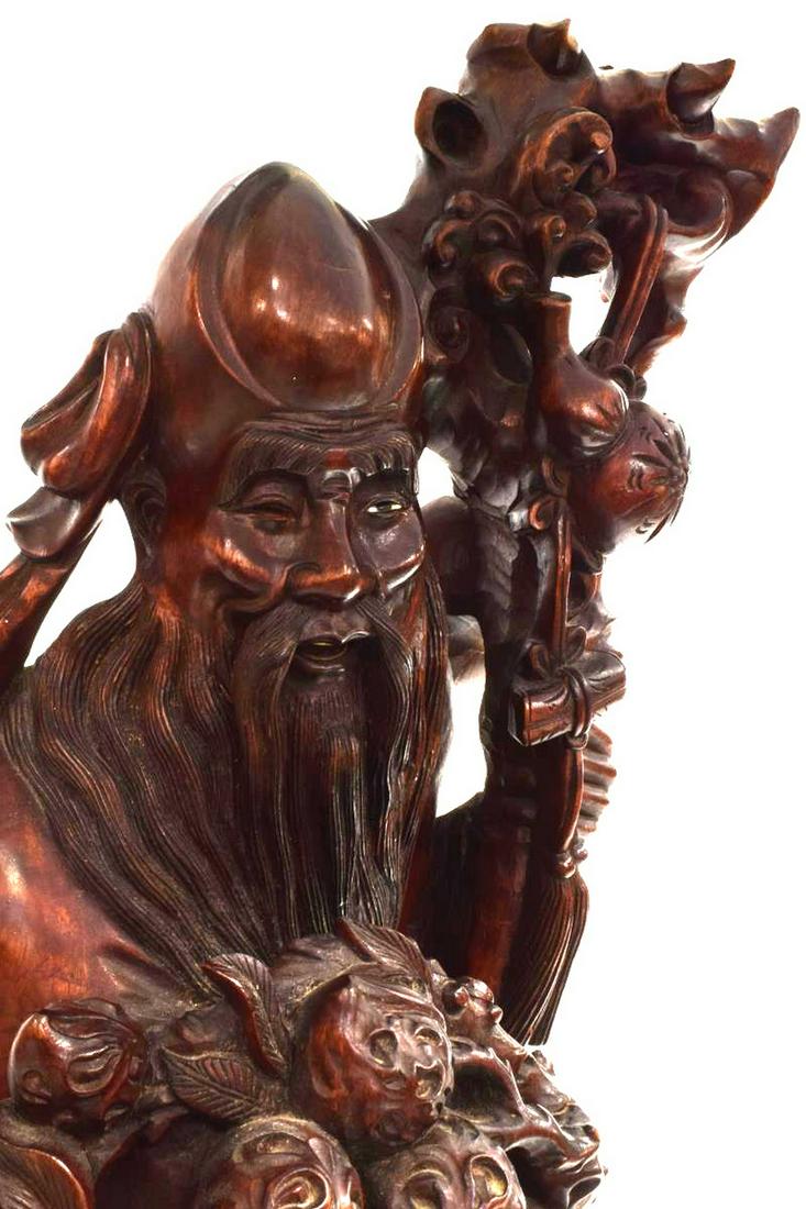 CHINESE CARVED WOOD SHOU LAO LONGEVITY FIGURE: Large Chinese carved wood longevity figure, 20th c., depicting Shou Lao with staff, surrounded by two children, one holding a bat, seated on a deer, the other with a crane, on a naturalistic base, res