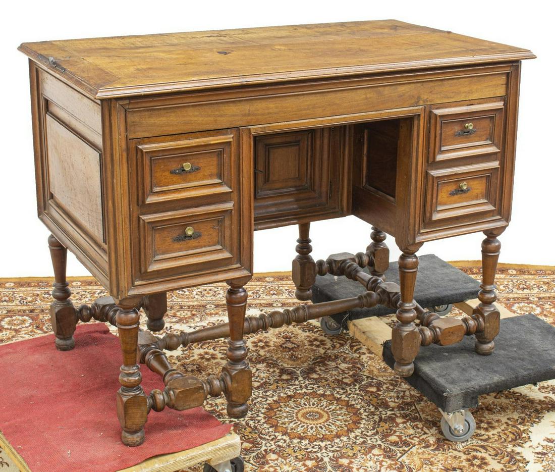FRENCH HINGED-TOP WALNUT WRITING DESK: French walnut writing desk, 19th c., hinged top over fall-front panel, four small drawers around the center kneehole, paneled cabinet door at back of kneehole, rising on turned stretcher-joined legs, 