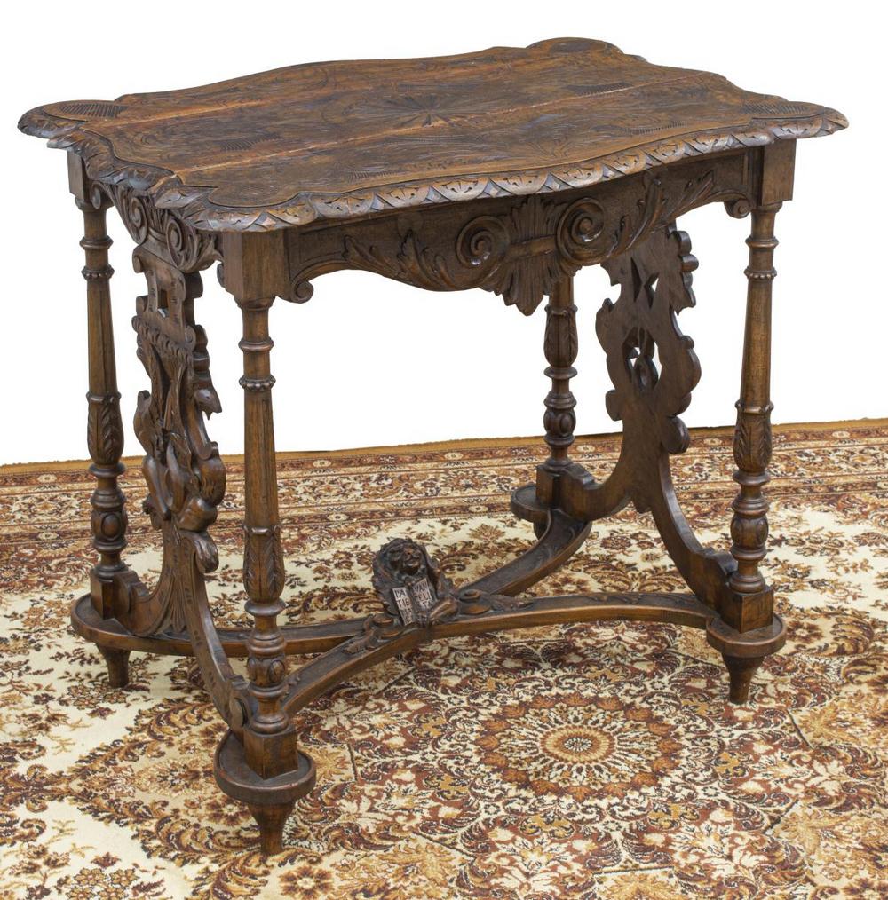 ITALIAN RENAISSANCE REVIVAL SAINT MARK LION TABLE: Italian Renaissance Revival walnut table, late 19th c., cartouche-shaped top with incised work, lunette-carved edge, supports with carved griffins, turned legs joined by cross stretcher, center orname