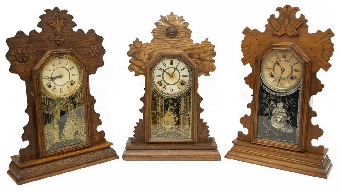 (3) AMERICAN GINGERBREAD KITCHEN SHELF CLOCKS: (lot of 3) American kitchen clocks, late 19th/ early 20thc., each in a "gingerbread" press carved wood case, retaining key and pendulum, comprising: (1) Ingram and Co., having time and strike movement