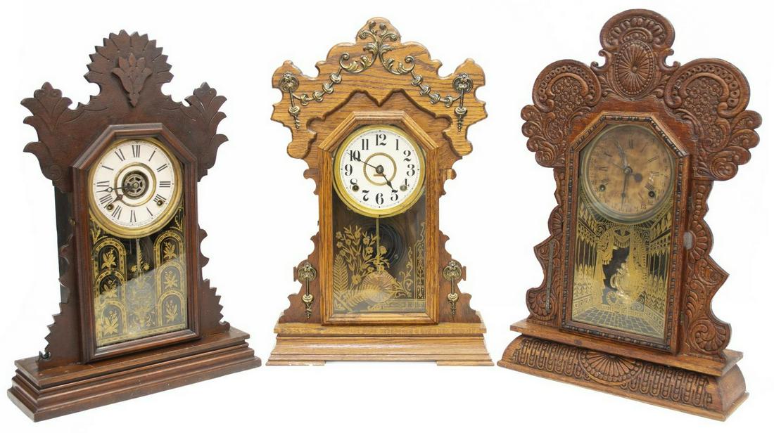 (3) AMERICAN GINGERBREAD KITCHEN SHELF CLOCKS: (lot of 3) American kitchen clocks, late 19th/ early 20thc., each in a "gingerbread" press carved wood case, retaining key and pendulum, comprising: (1) Seth Thomas, having time and strike movement, p