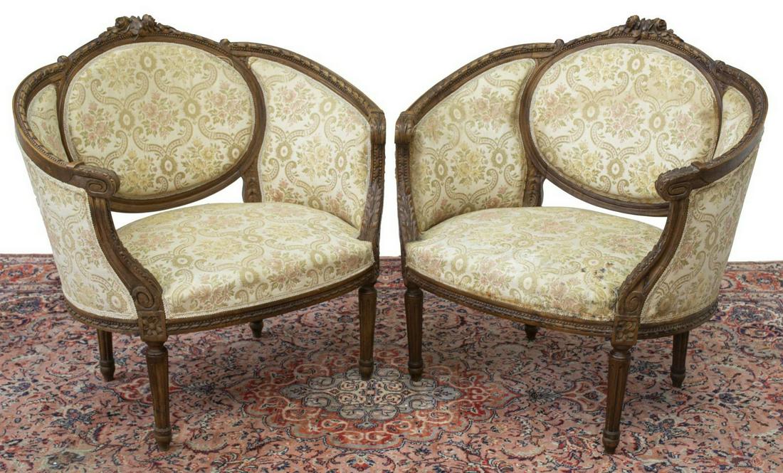 (2) LOUIS XVI STYLE FINELY CARVED CURVED BERGERES: (pair) Louis XVI style curved end armchairs, early 20thc., a carved foliate crest rail over padded back and seat with carved skirt, rising on tapered legs with blunt arrow feet, stains and wear to uph